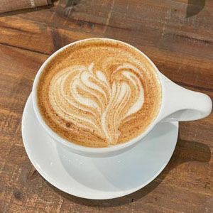 White cup of latte with heart-shaped foam art on a wooden table