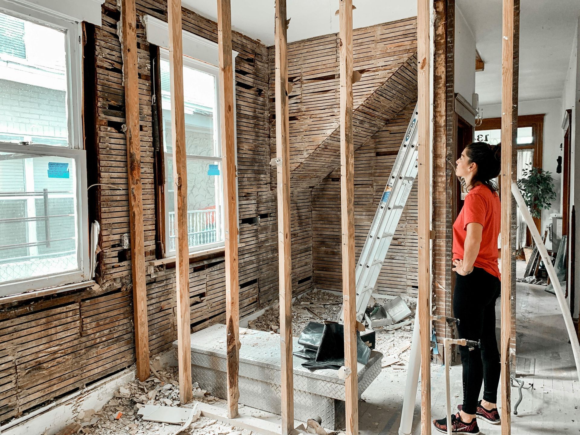 Eine Person in einem roten Hemd steht in einem Raum mit freiliegenden Wandständern und betrachtet eine im Bau Treppe.