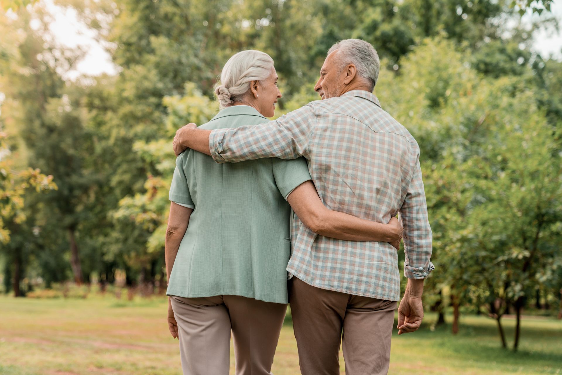 An elderly couple hugging each other on a rooftop at sunset.