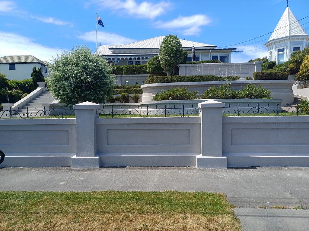 A large white house is behind a white fence
