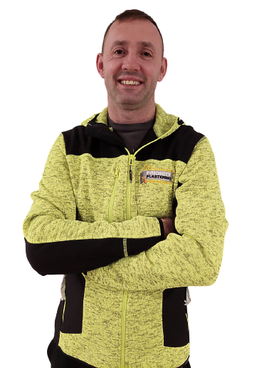 A man in a yellow and black jacket is smiling with his arms crossed.