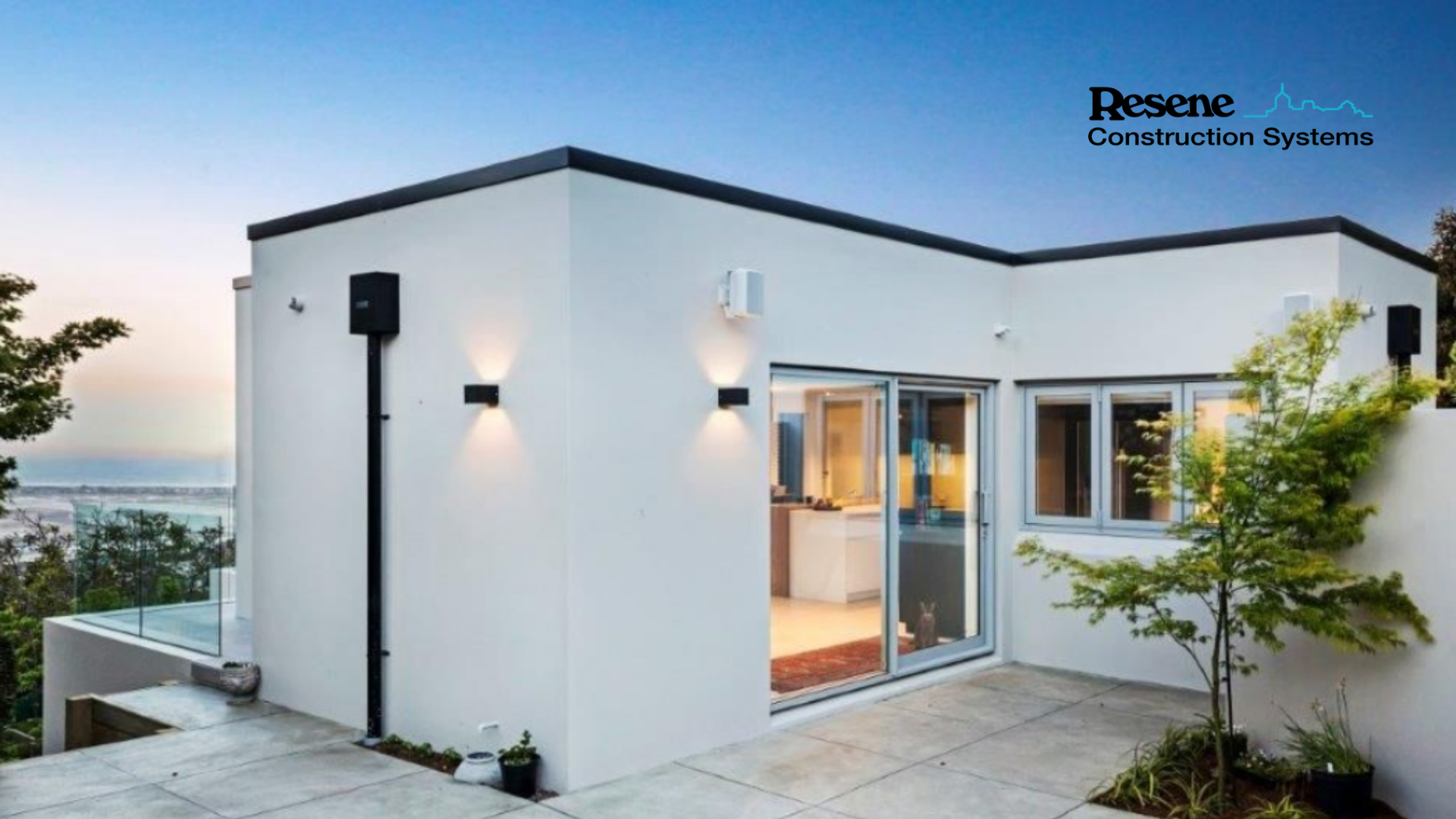 A white house with a sliding glass door is sitting on top of a hill.
