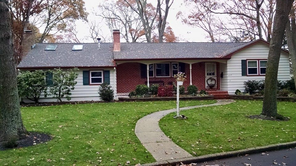 A ranch-style house with a brick facade and white siding, front porch, and a winding walkway.