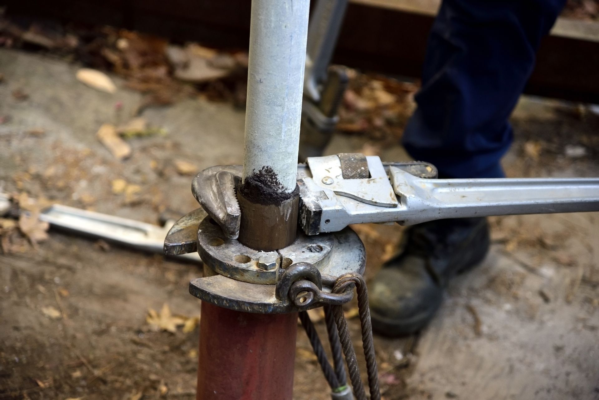 A technician is using pipe wrenches on a well casing during repair.