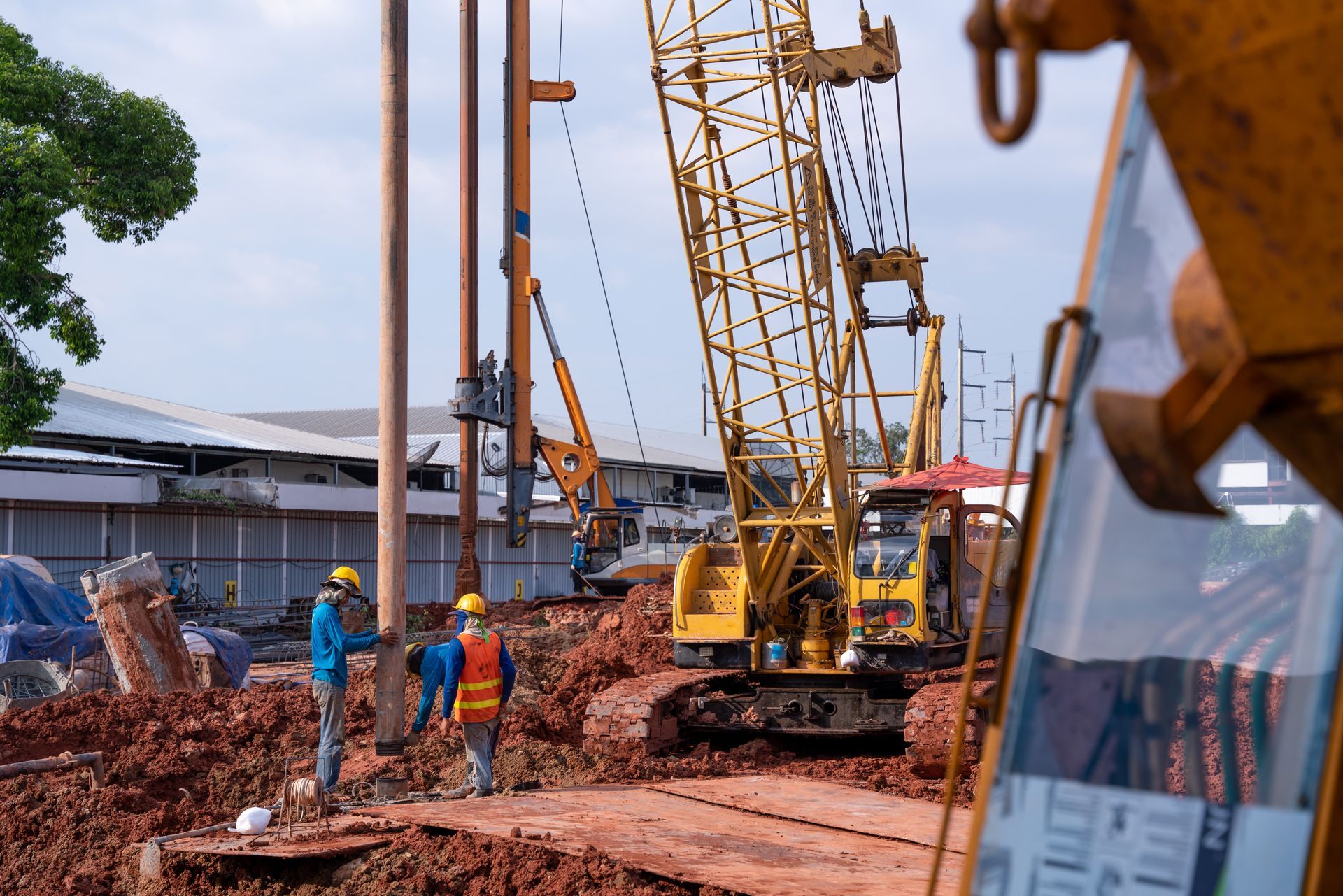 Construction site with workers and heavy drilling and piling equipment