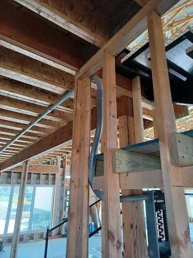 Wooden framing of a building under construction, with electrical conduit running through a wall.
