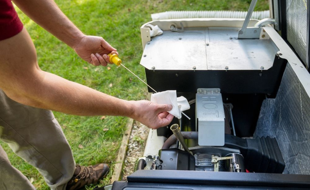 Person checks oil level in a generator with a dipstick, wiping it with a white cloth outdoors.