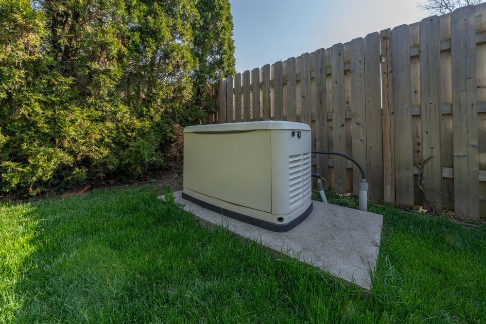 Exterior of a house with blue siding, a standby generator, and electrical boxes.