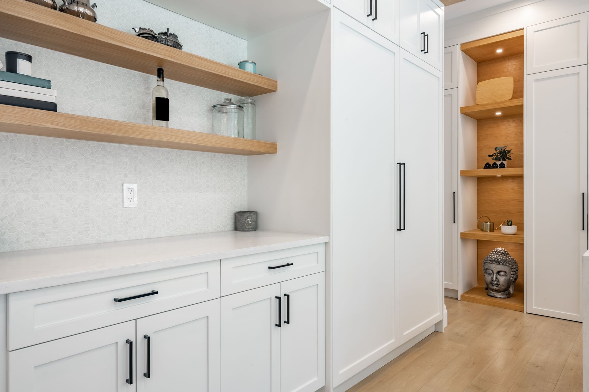 Modern white kitchen with wooden shelves, countertop, and cabinets; recessed shelves in the wall.