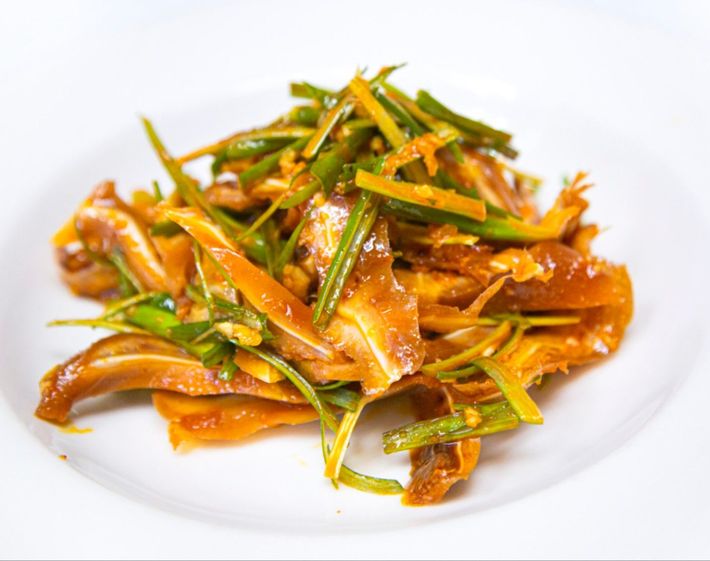 Plated stir-fried noodles with scallions and orange sauce on a white dish