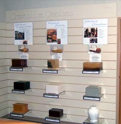 Display of school project models on wall shelves with posters above each item