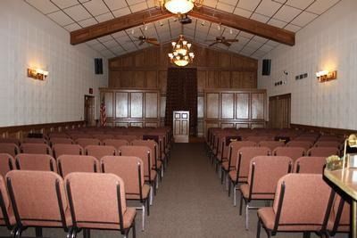 Empty meeting room with rows of pink chairs facing a wood-paneled front stage