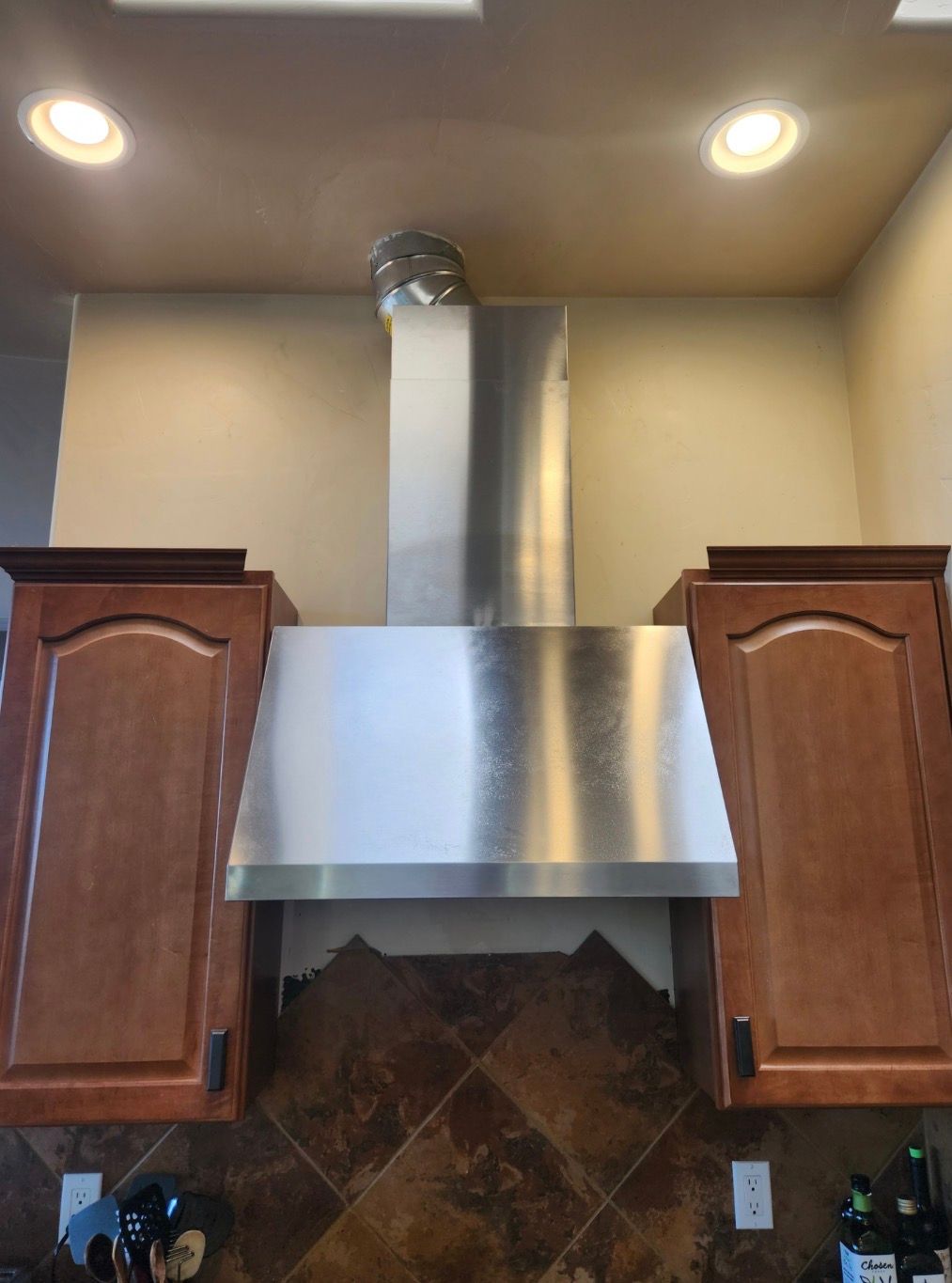 Tall wooden cabinet next to a stainless steel refrigerator in a kitchen.