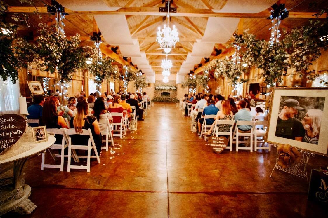 Elegant indoor wedding reception with long banquet tables, warm lights, and greenery decorations