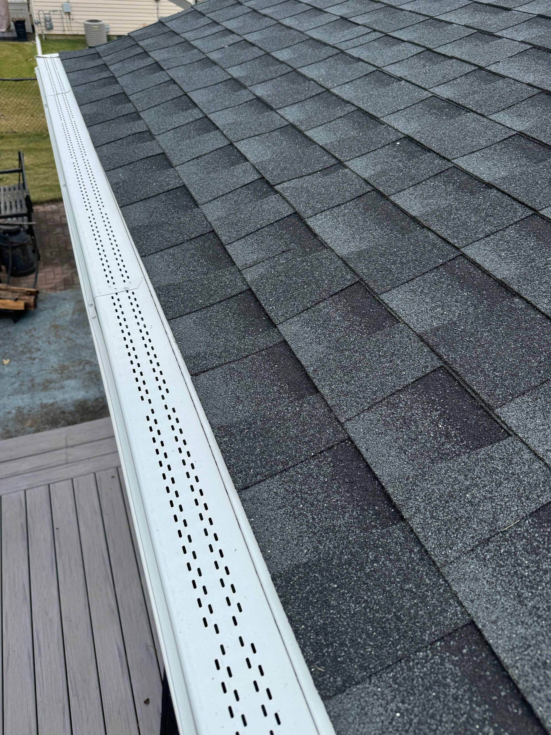 Roof with gray shingles and white perforated edge trim along the gutter.