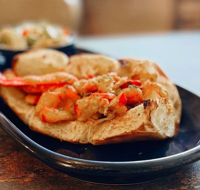 Lobster roll on a plate with a small side salad.
