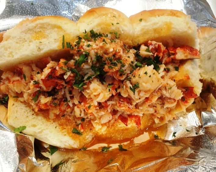 Sub sandwich stuffed with shredded filling and herbs on foil