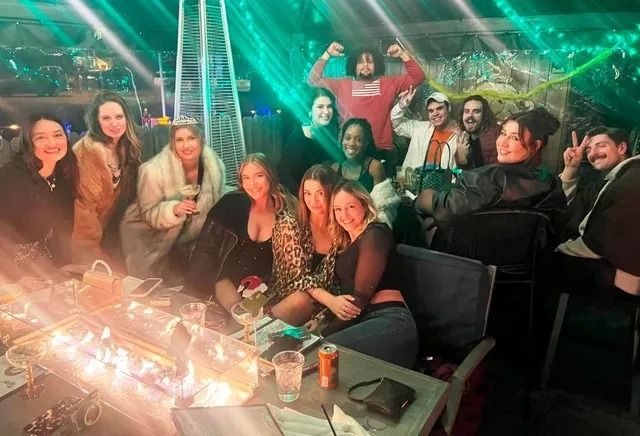 Group of people at an outdoor lounge with a fire pit, posing for a photo.