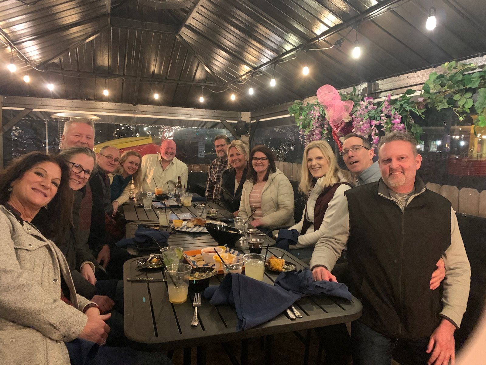 Group of people seated around a table, dining at an outdoor restaurant.