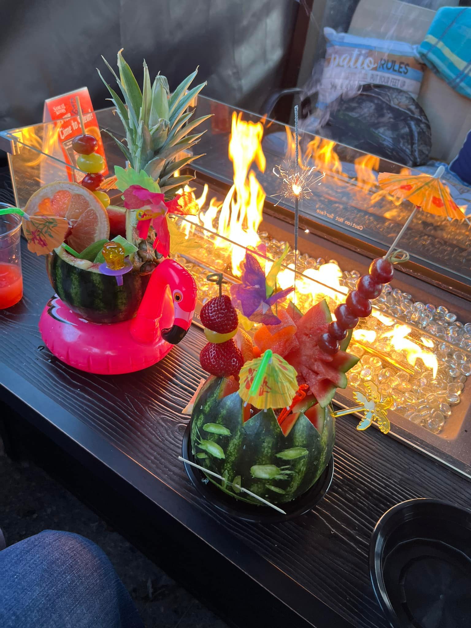 Watermelon cocktail bowls with fruit skewers, sparklers, and a fire pit.
