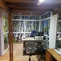 Espacio de trabajo interior con escritorio, monitores de computadora y silla cubierta de plástico en una habitación.