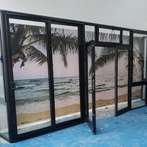 Puertas de cristal con marcos negros y un mural que representa una escena de playa, sobre un suelo azul.