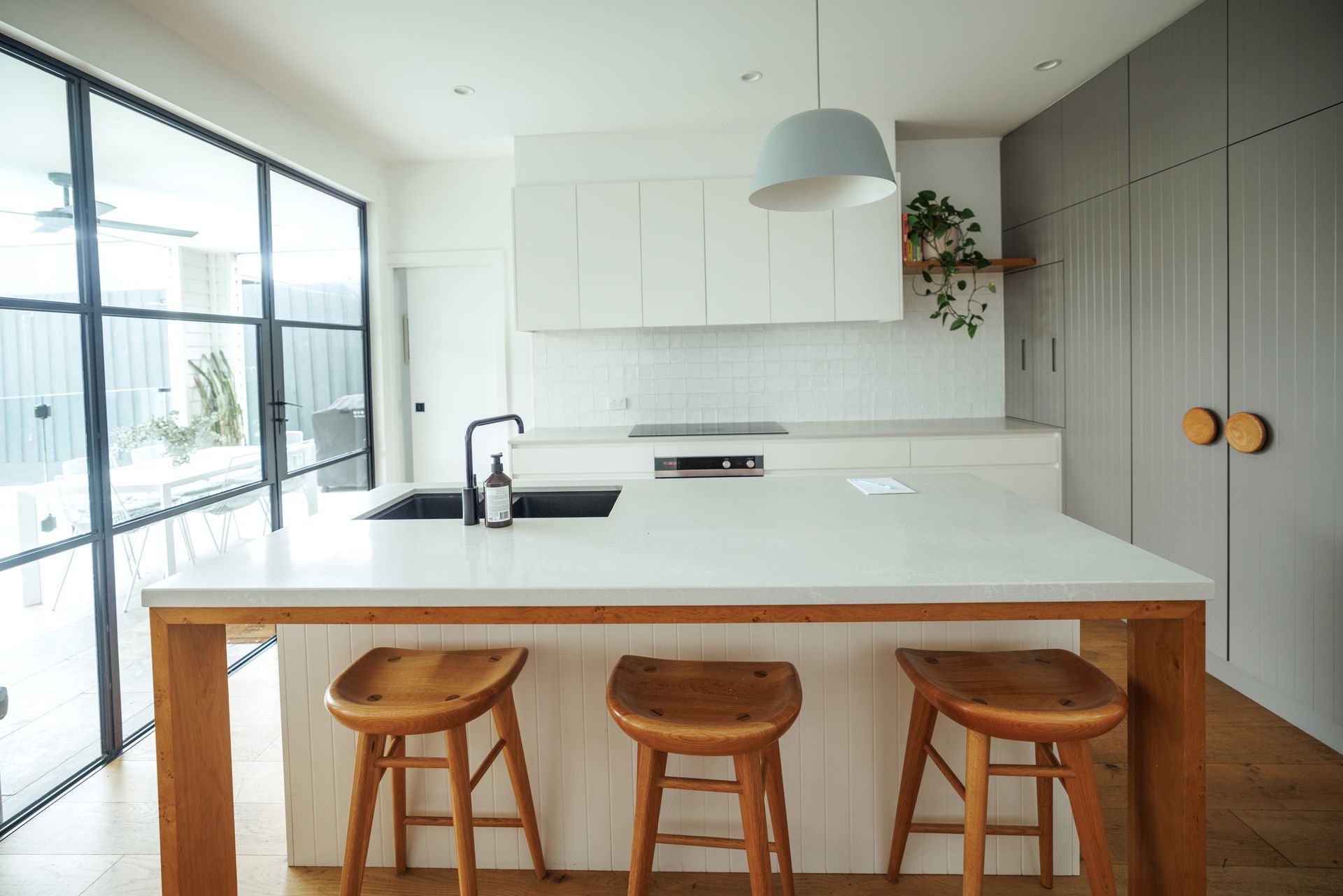 A kitchen with a large island and three wooden stools.