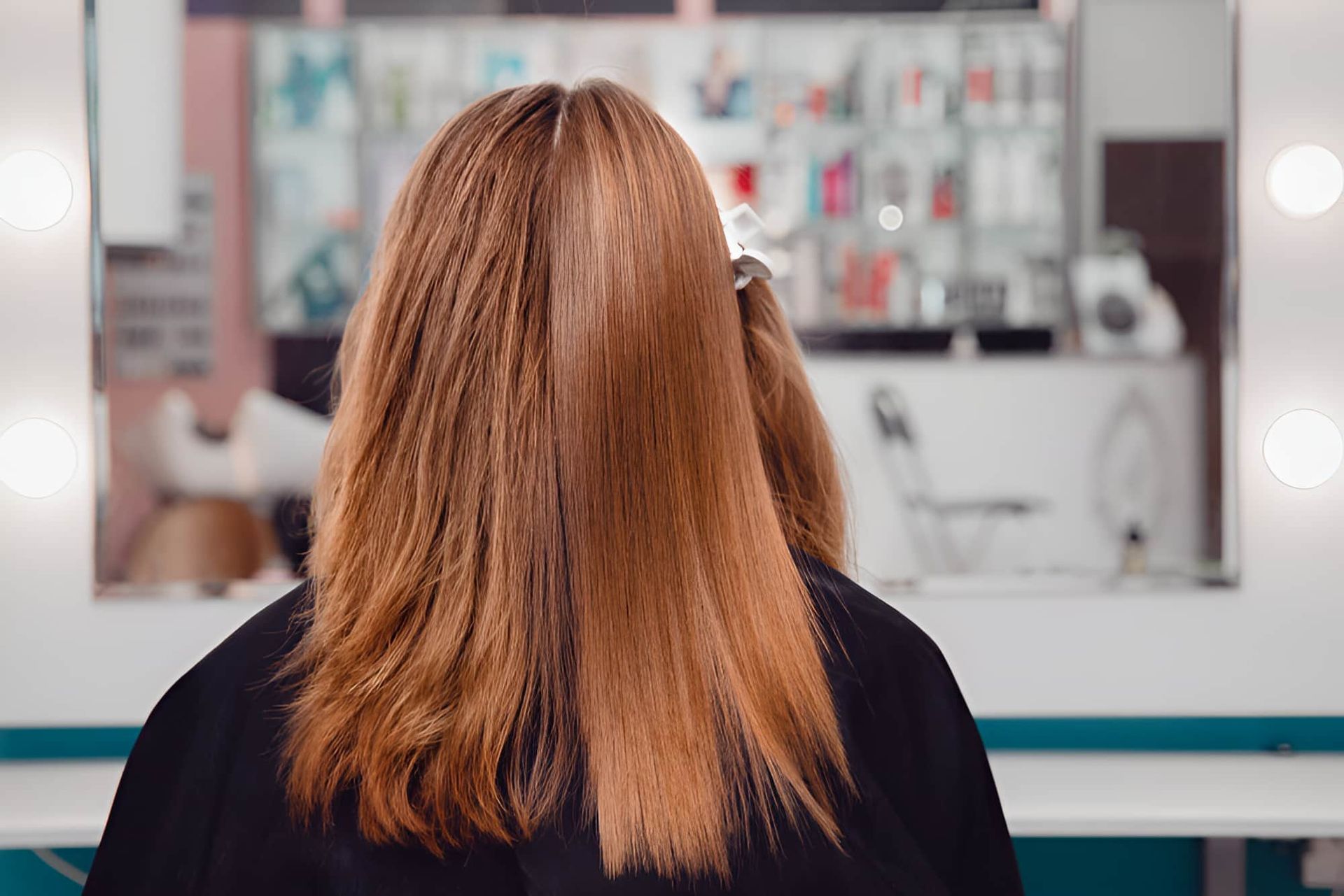 A Woman Is Sitting In Front Of A Mirror In A Hair Salon — Kabello Salon In Airlie Beach, QLD
