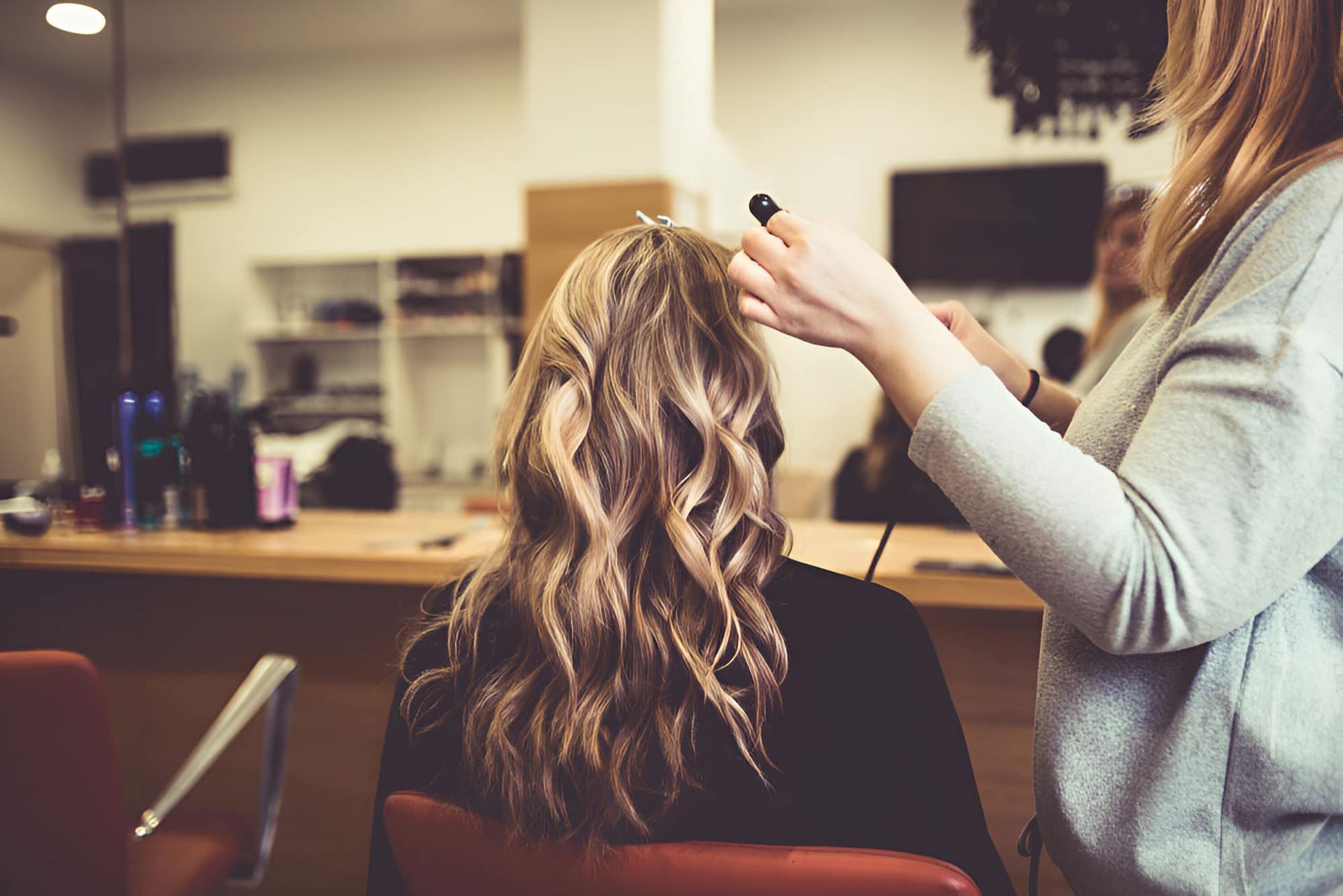A Woman Is Getting Her Hair Done By A Hairdresser In A Salon — Kabello Salon In Airlie Beach, QLD
