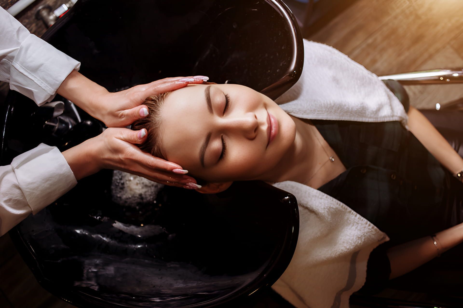 A Woman Is Getting Her Hair Washed In A Salon — Kabello Salon In Airlie Beach, QLD