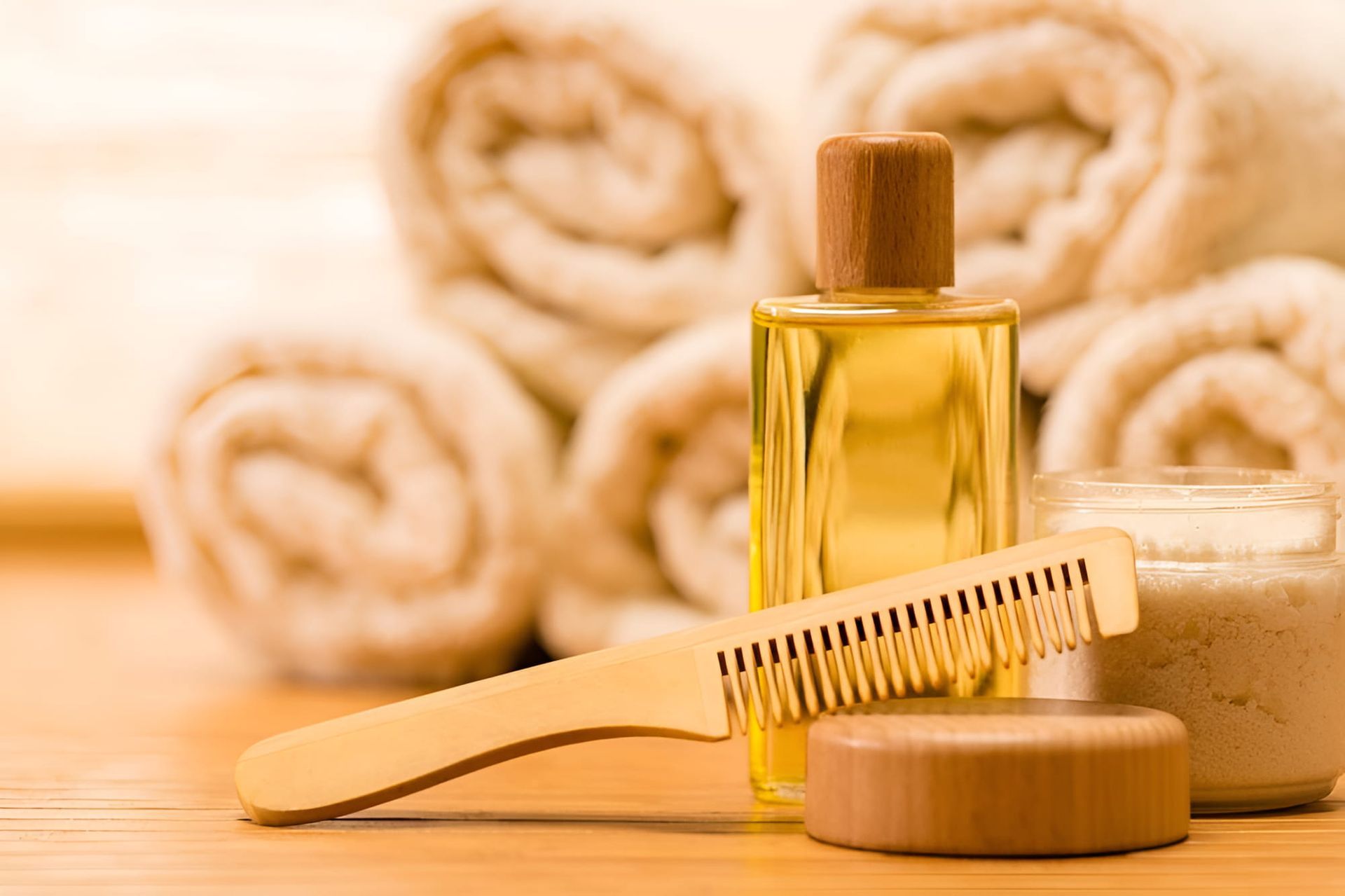 A Wooden Comb Is Sitting On A Wooden Table Next To A Bottle Of Oil — Kabello Salon In Airlie Beach, QLD