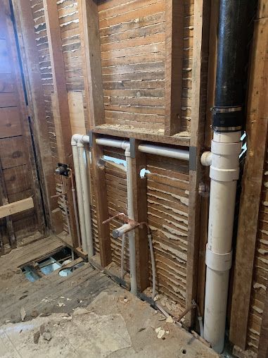 A bathroom with a lot of pipes coming out of the wall.