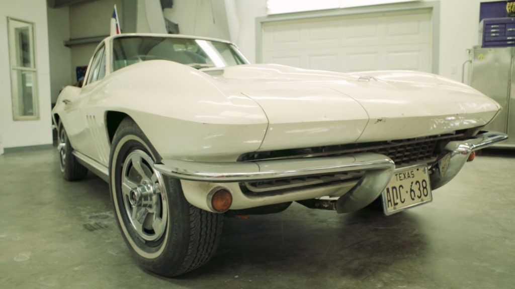 White classic Corvette in a garage, front view.
