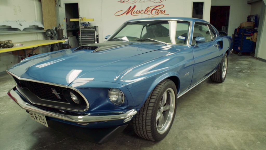 Blue 1969 Ford Mustang Mach 1 muscle car in a garage.