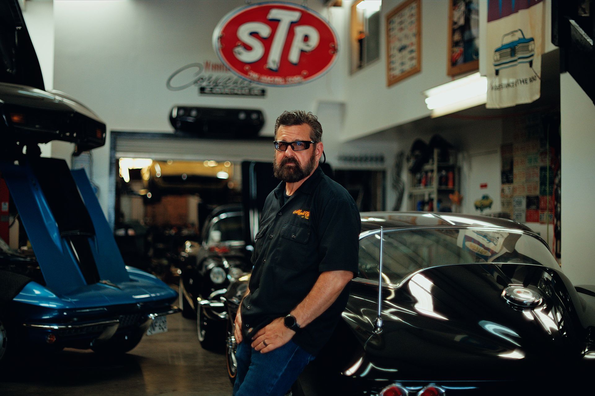 Man standing between two white classic muscle cars in front of a