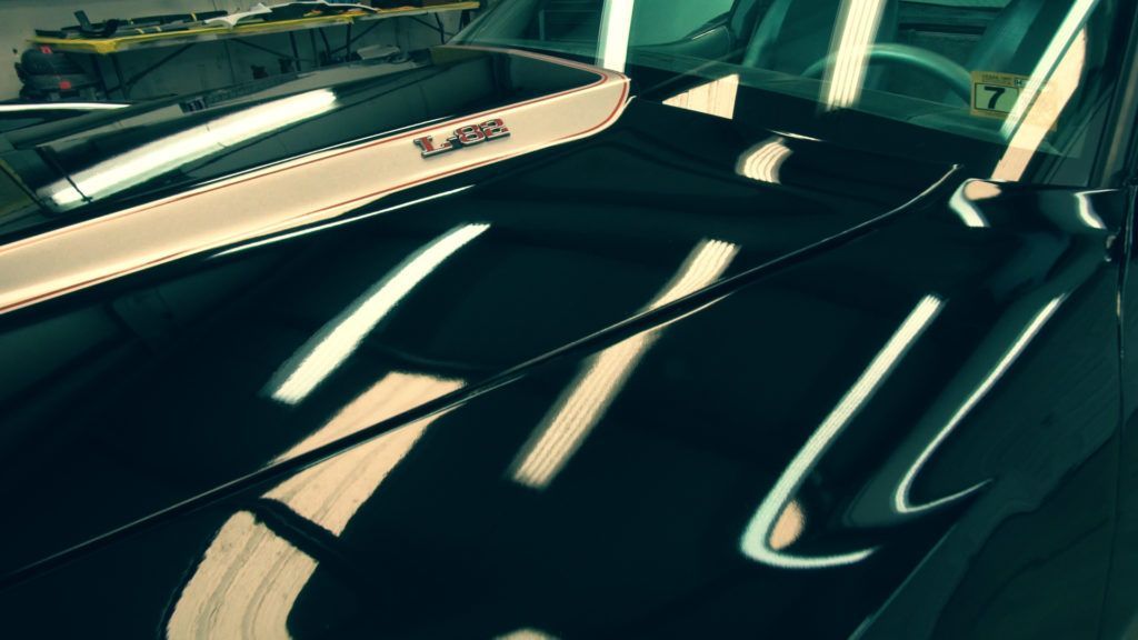 Black classic car hood reflecting light.