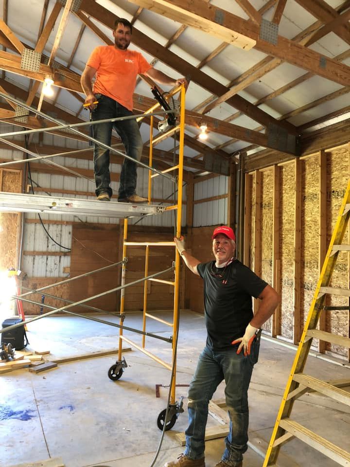 Two men are standing on a scaffolding in a building.