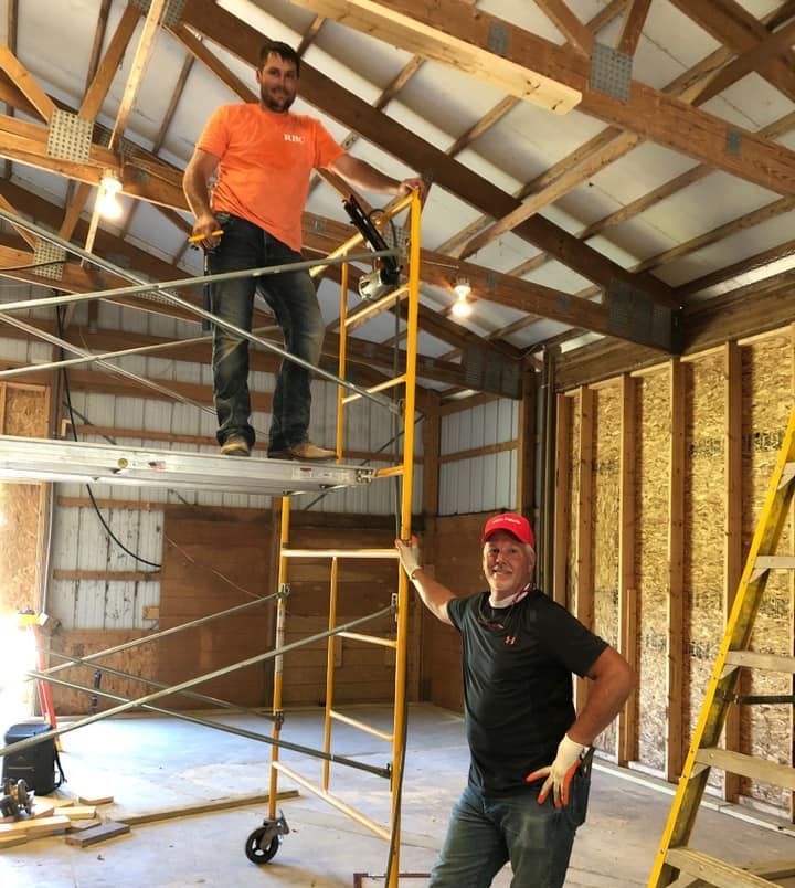 Two construction workers are working on the roof of a house.