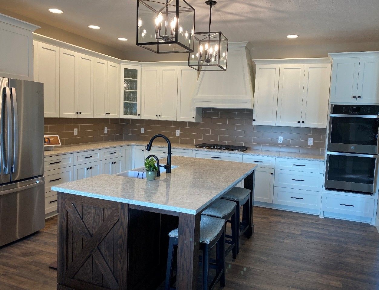A kitchen with white cabinets, stainless steel appliances, and a large island.