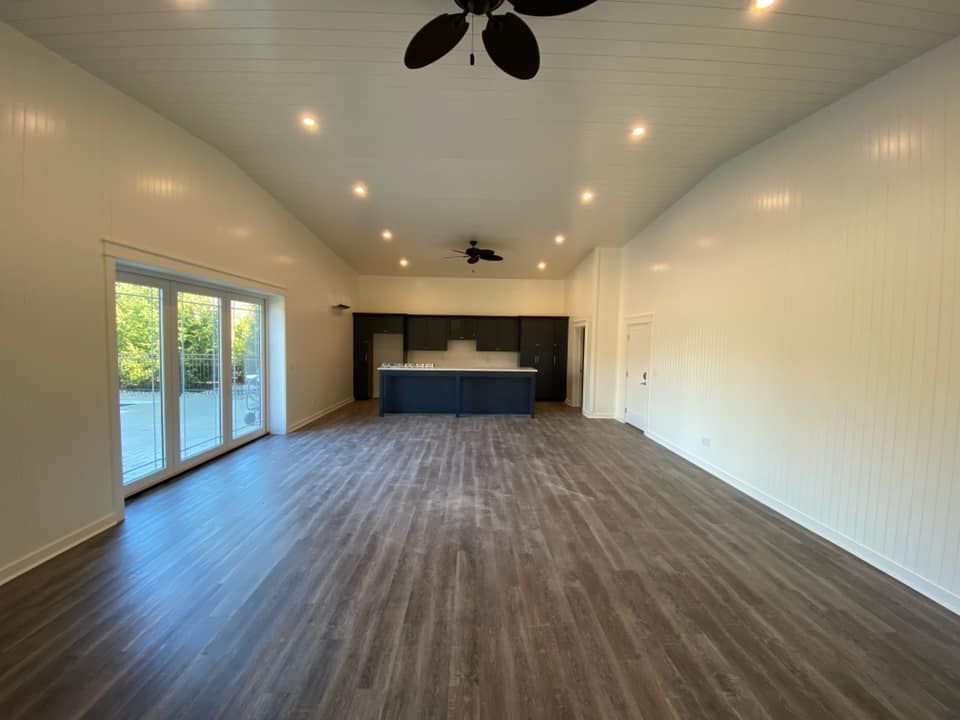 A large empty room with hardwood floors and a ceiling fan.