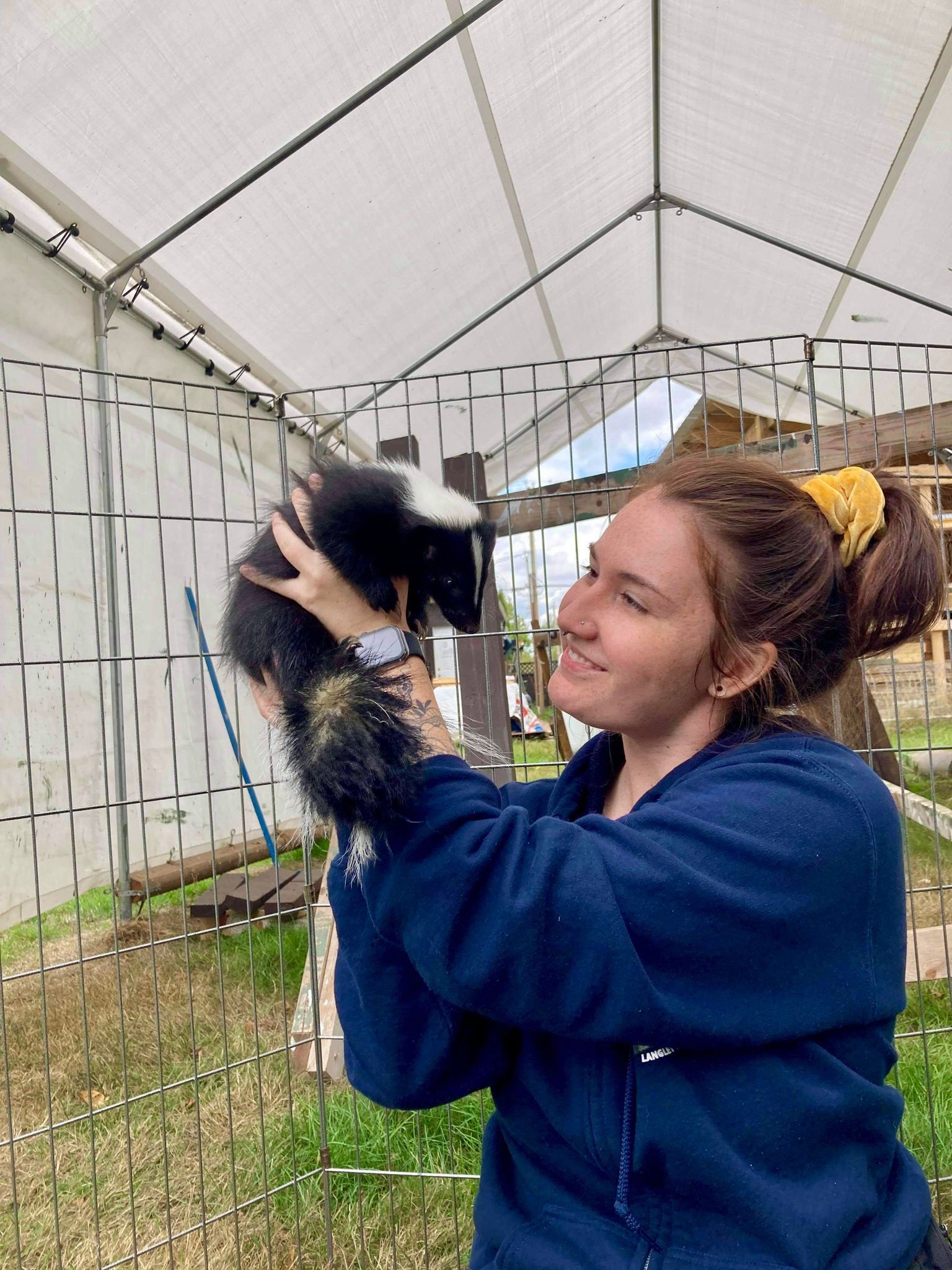 A woman is holding a small black and white animal in her arms.