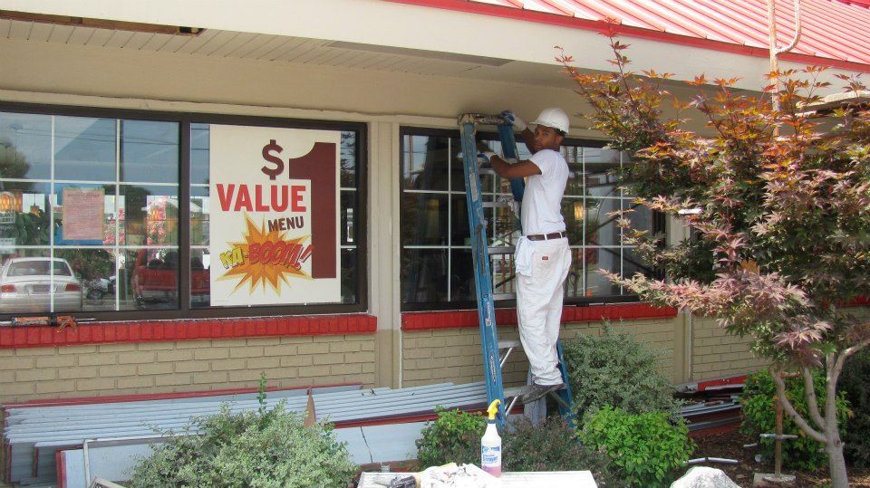 Man on ladder painting building's exterior near 