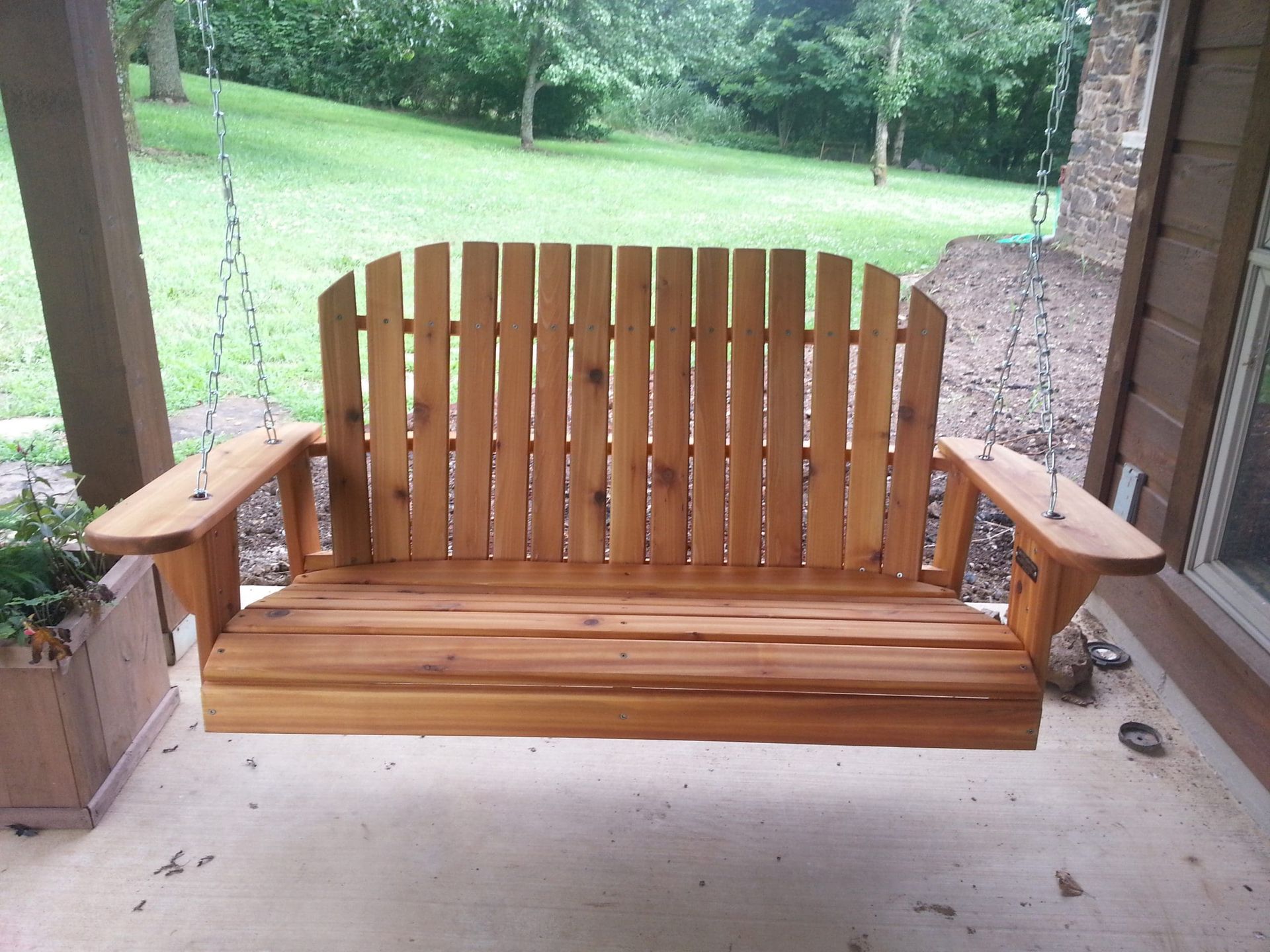 A wooden porch swing with a fence in the background