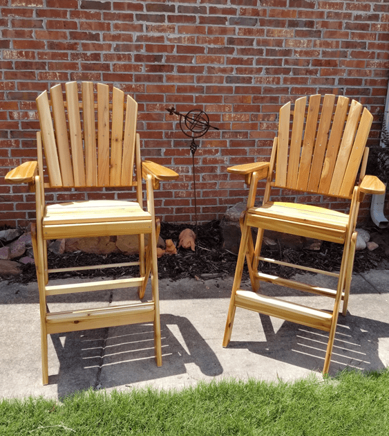 Two wooden chairs are sitting in front of a brick wall