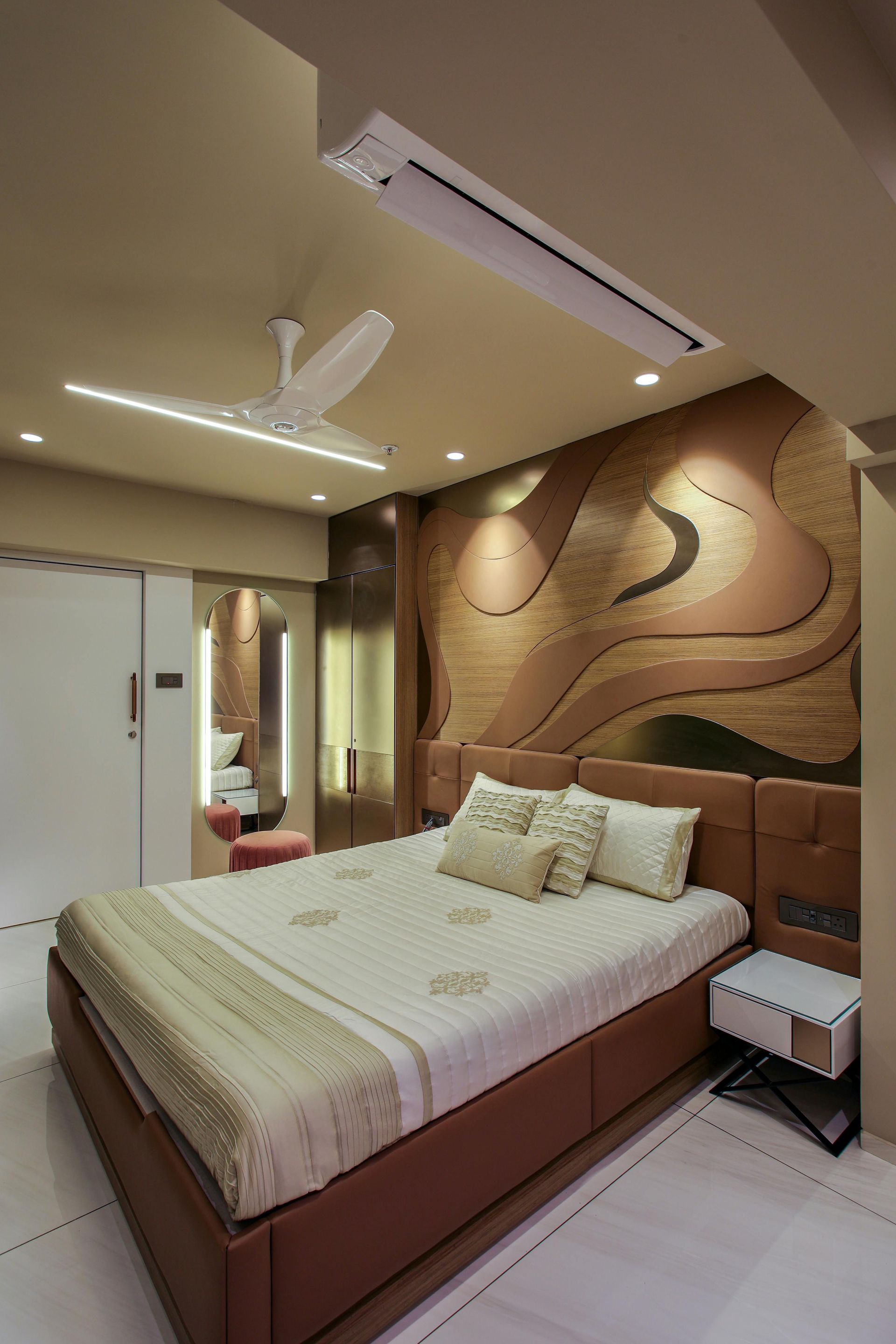 Bedroom with brown bed, decorative wall, and white ceiling fan.