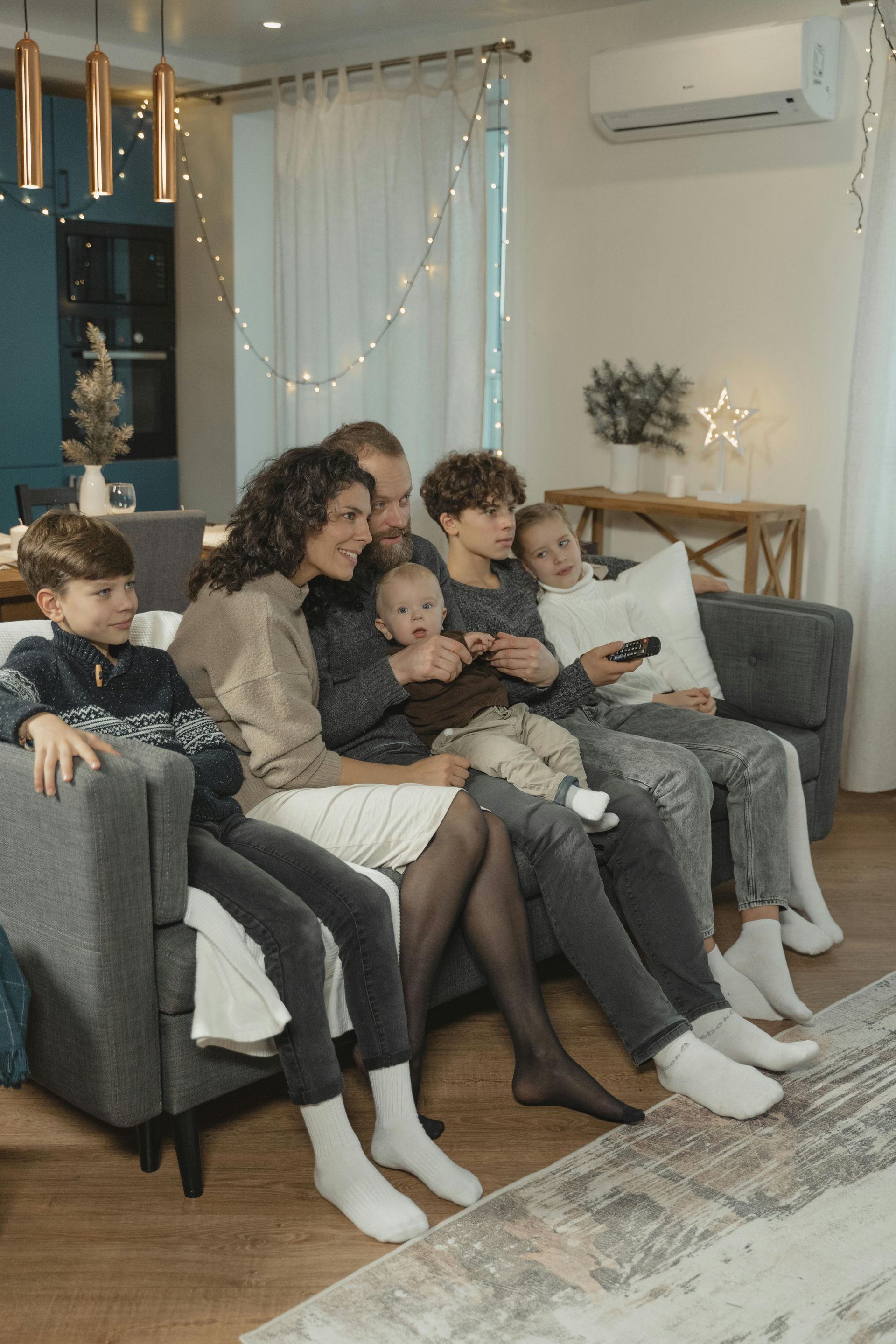 Family watches TV together on a couch, living room setting.