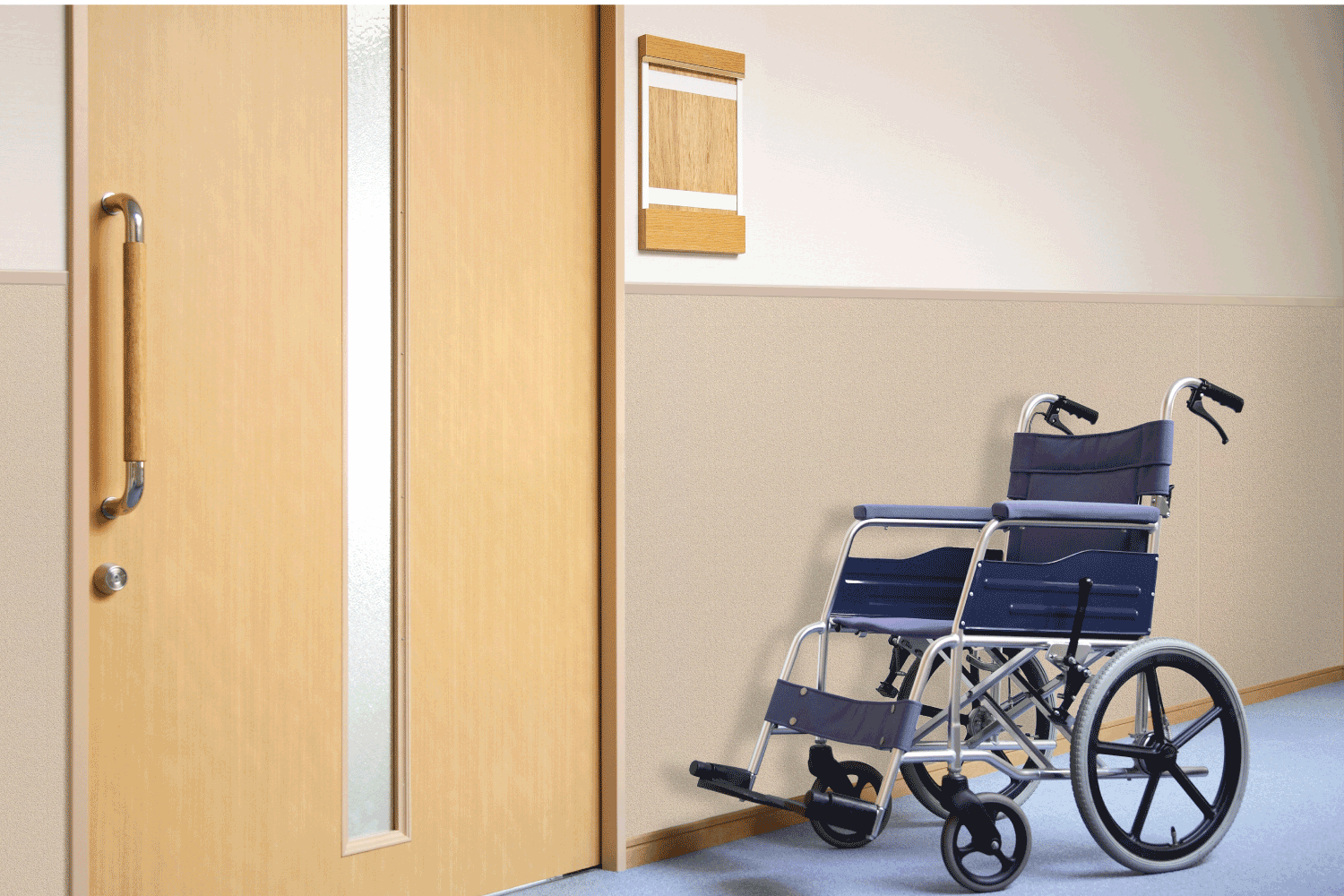 A wheelchair is parked in a hallway next to a door.