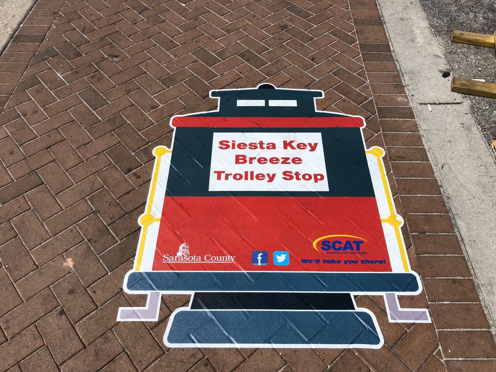 A sign on the sidewalk that says siesta key breeze trolley stop