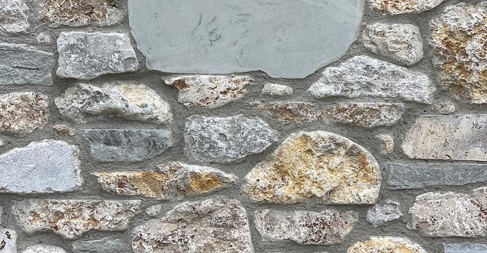 A close up of a stone wall with a blue stone in the middle.