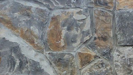 A close up of a stone wall with a lot of different colored rocks.